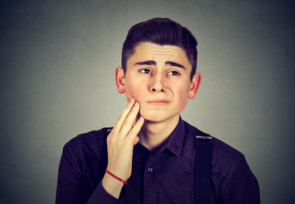 Young man holding his cheek in pain
